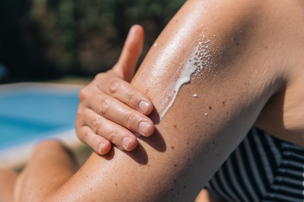 close up of hand applying sunscreen to arm