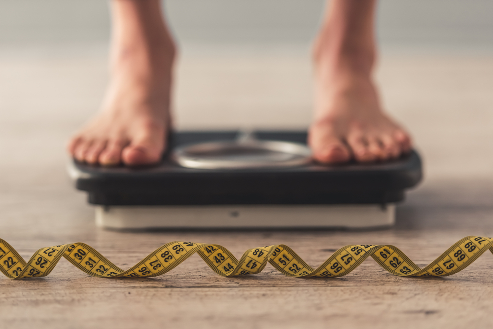 tape measure in front of feet standing on scale